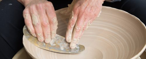 Mary Fox's hands working on a decorative bowl thrown on the wheel